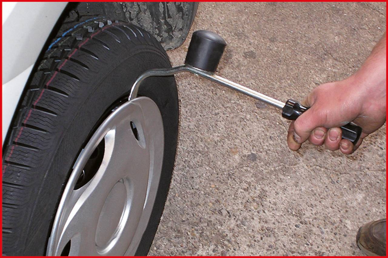 A person is tightening a wheel nut with a tool on a car tyre.