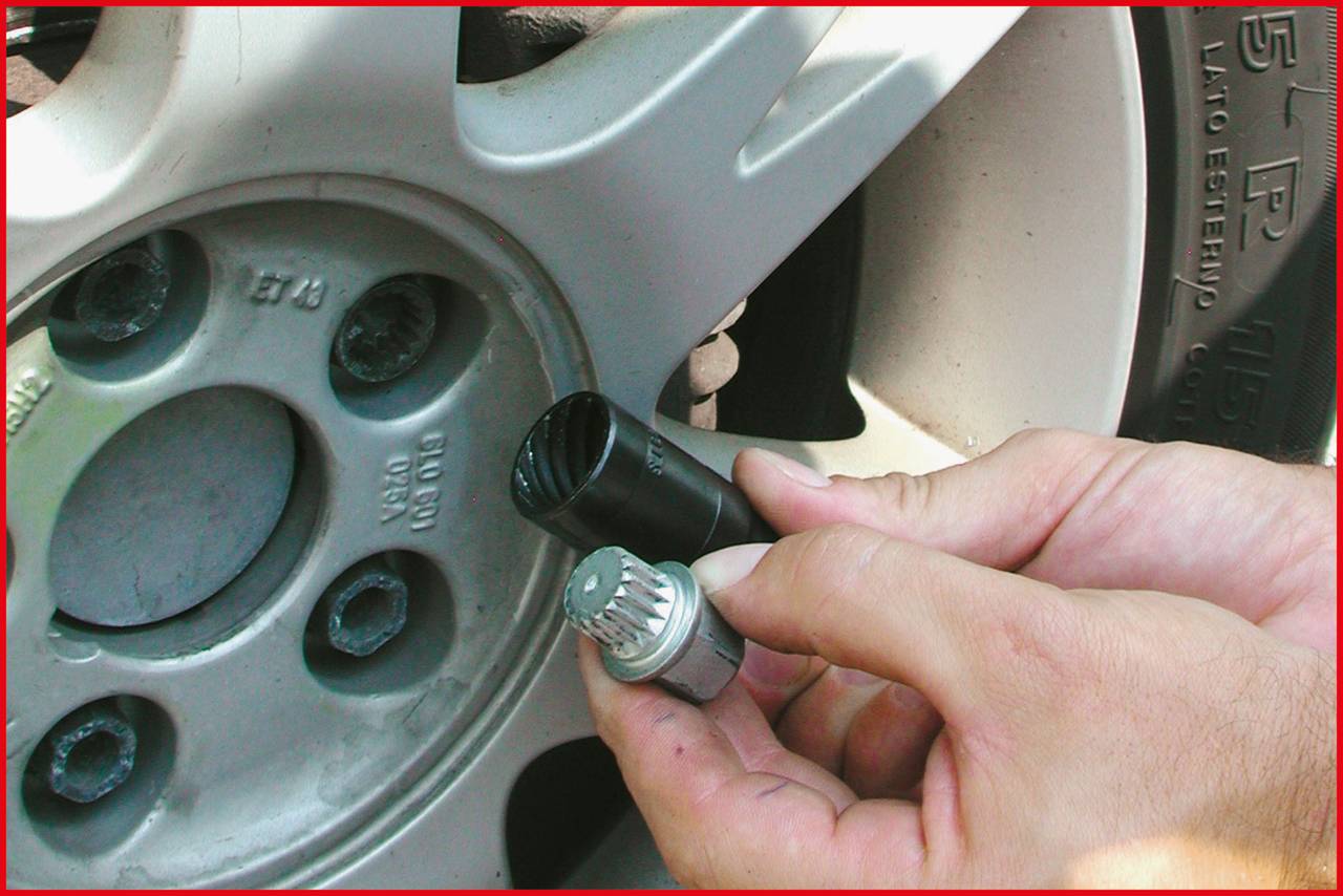 A hand is fitting a wheel nut on a car tyre.