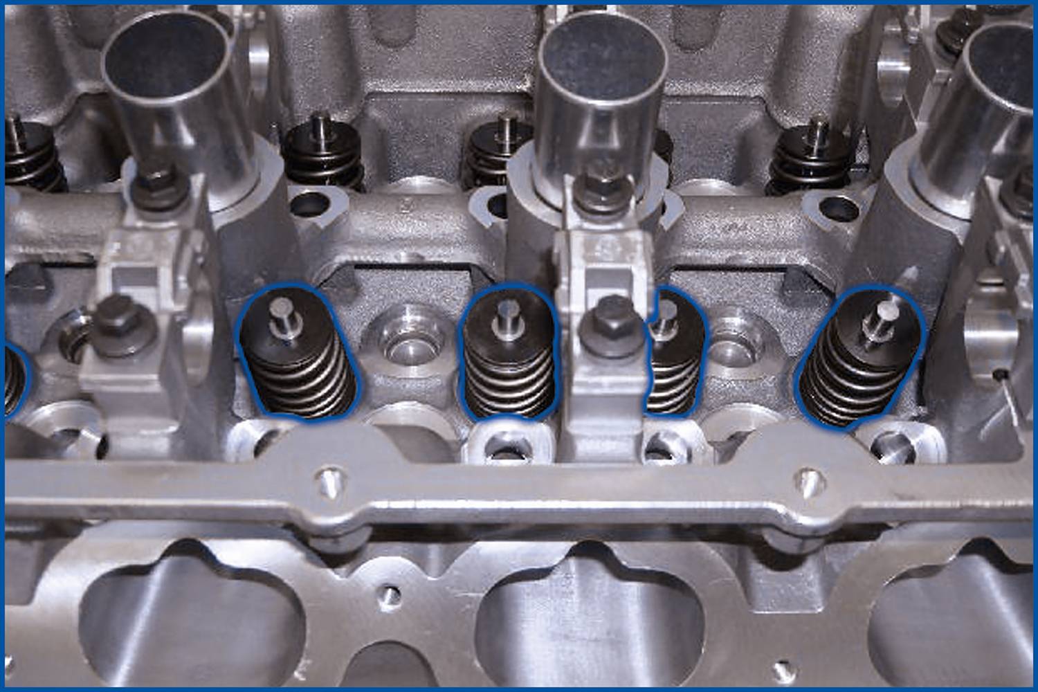 Close-up of an engine cylinder head with valves and springs, showcasing the complex mechanics and design of the engine.