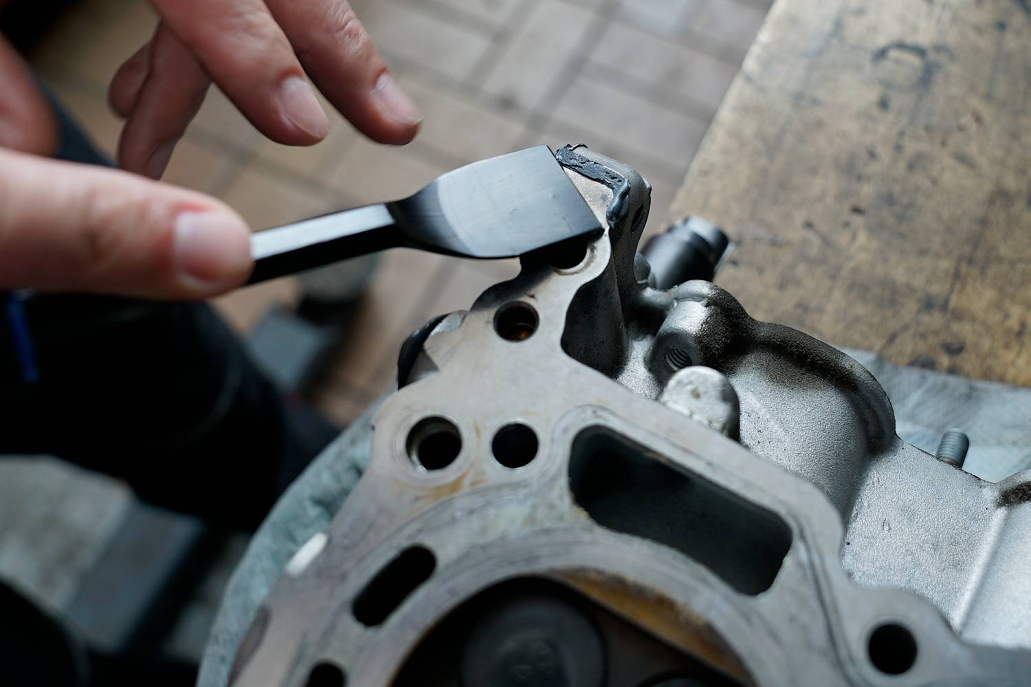 Someone is applying sealant to the metal surface of a car part.