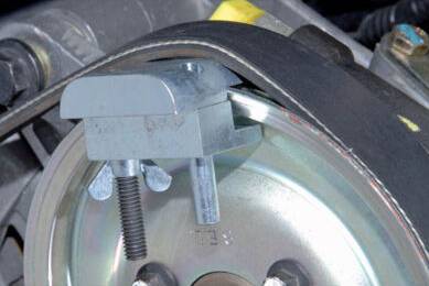 A solid metal wedge tensions a belt around a metal disc in a mechanical device to maintain tension.