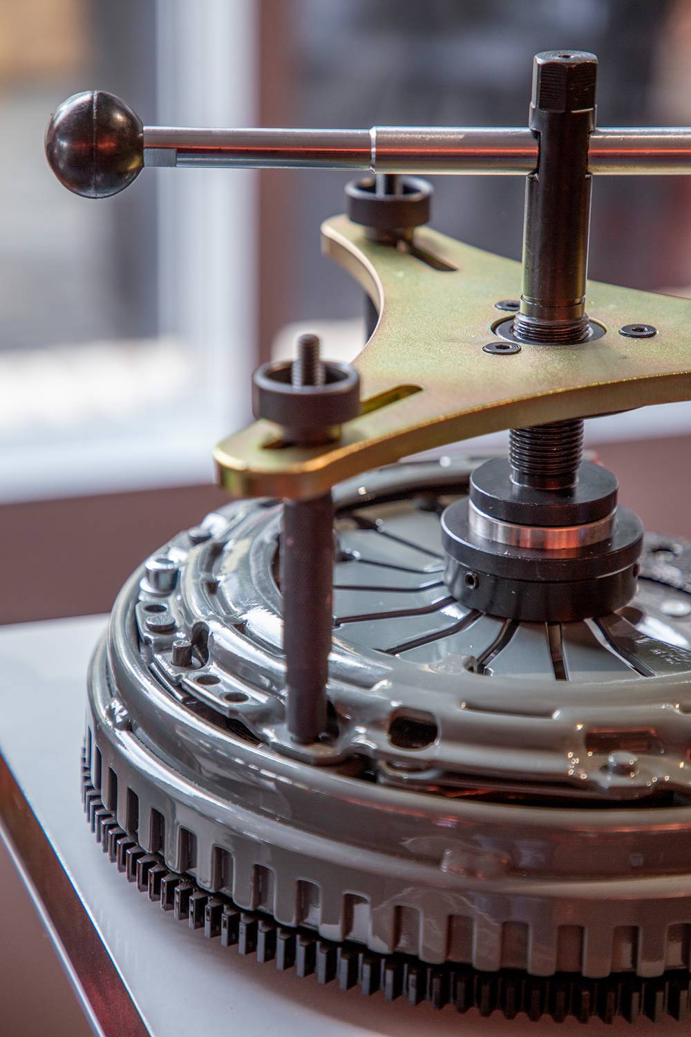 'Close-up of a mechanical device with a rotating arm and gears, placed on a table in a well-lit room.'
