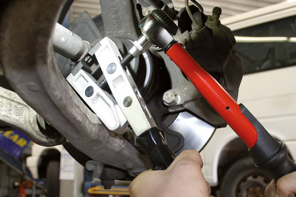 A mechanic uses specialist tools to repair a car part. Close-up of repair work in a workshop environment.