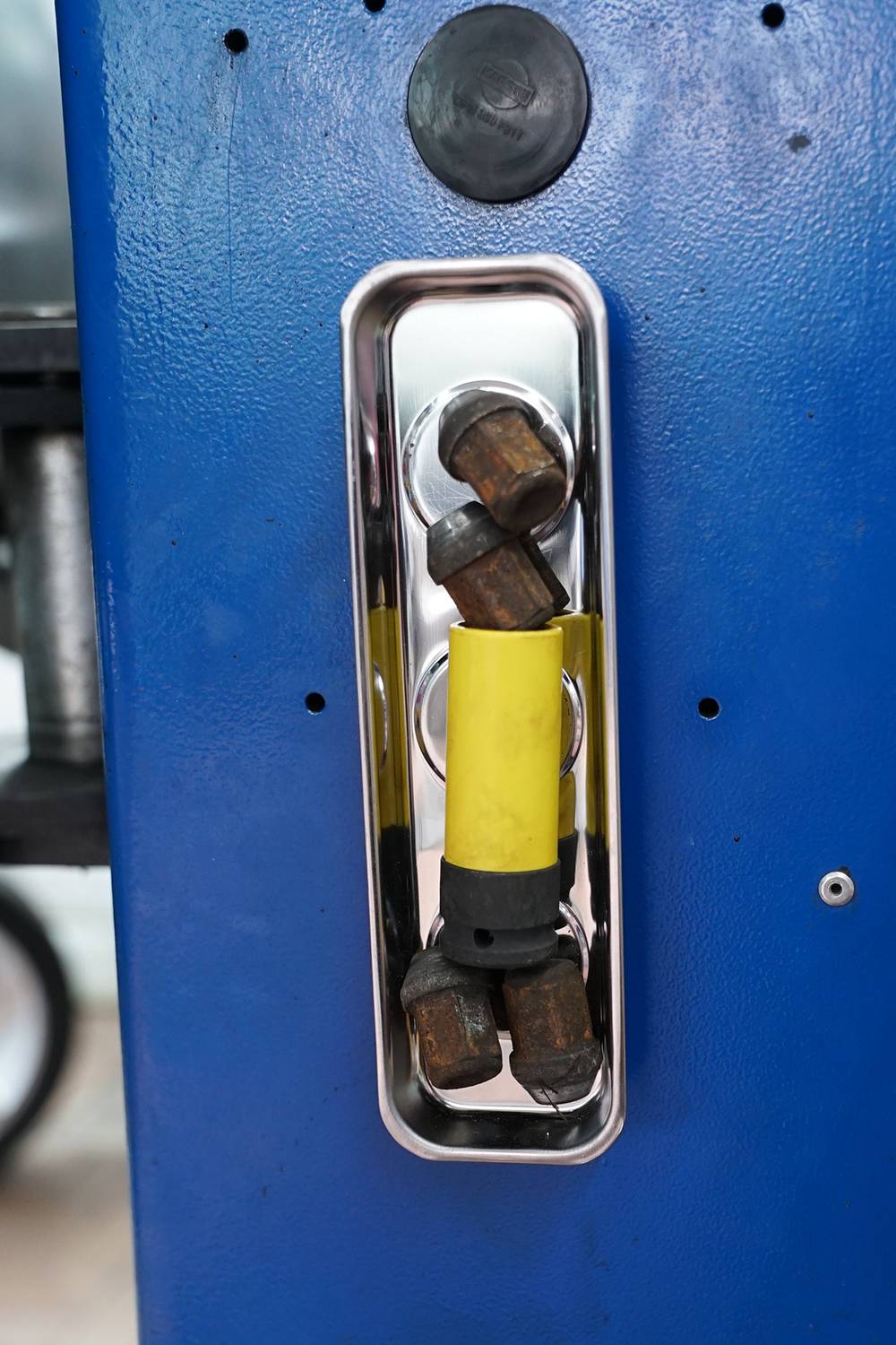'Three metal pieces with yellow handles in a blue holder on a machine.'