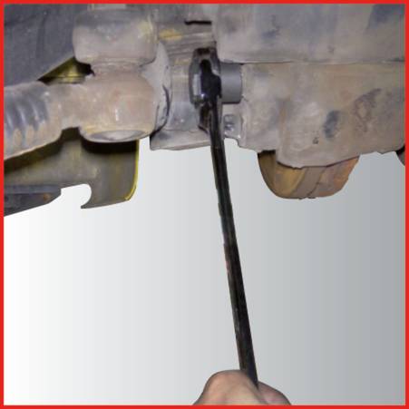A person is using a spanner to loosen a screw on a vehicle component.