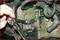 A person tightens a screw in an engine compartment using a ratchet tool. Close-up of various engine components.
