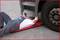 A person in work attire is lying underneath a lorry, apparently carrying out repair work, on a padded mat.
