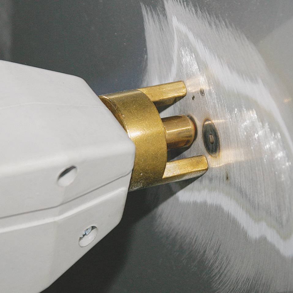 Close-up of a white plug partially inserted into a grey wall socket, with golden metal contacts visible.