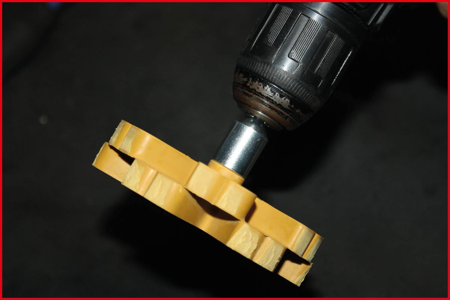 'Attachment inserted into drill, ready for use. The attachment is yellow, round in shape, with serrated edges.'