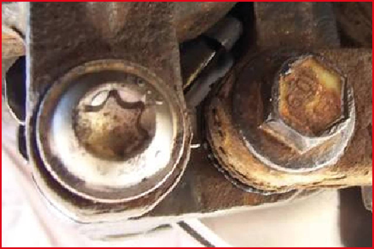 'Close-up of two rusted screws on a metal part. One is round, the other has a hexagonal profile.'