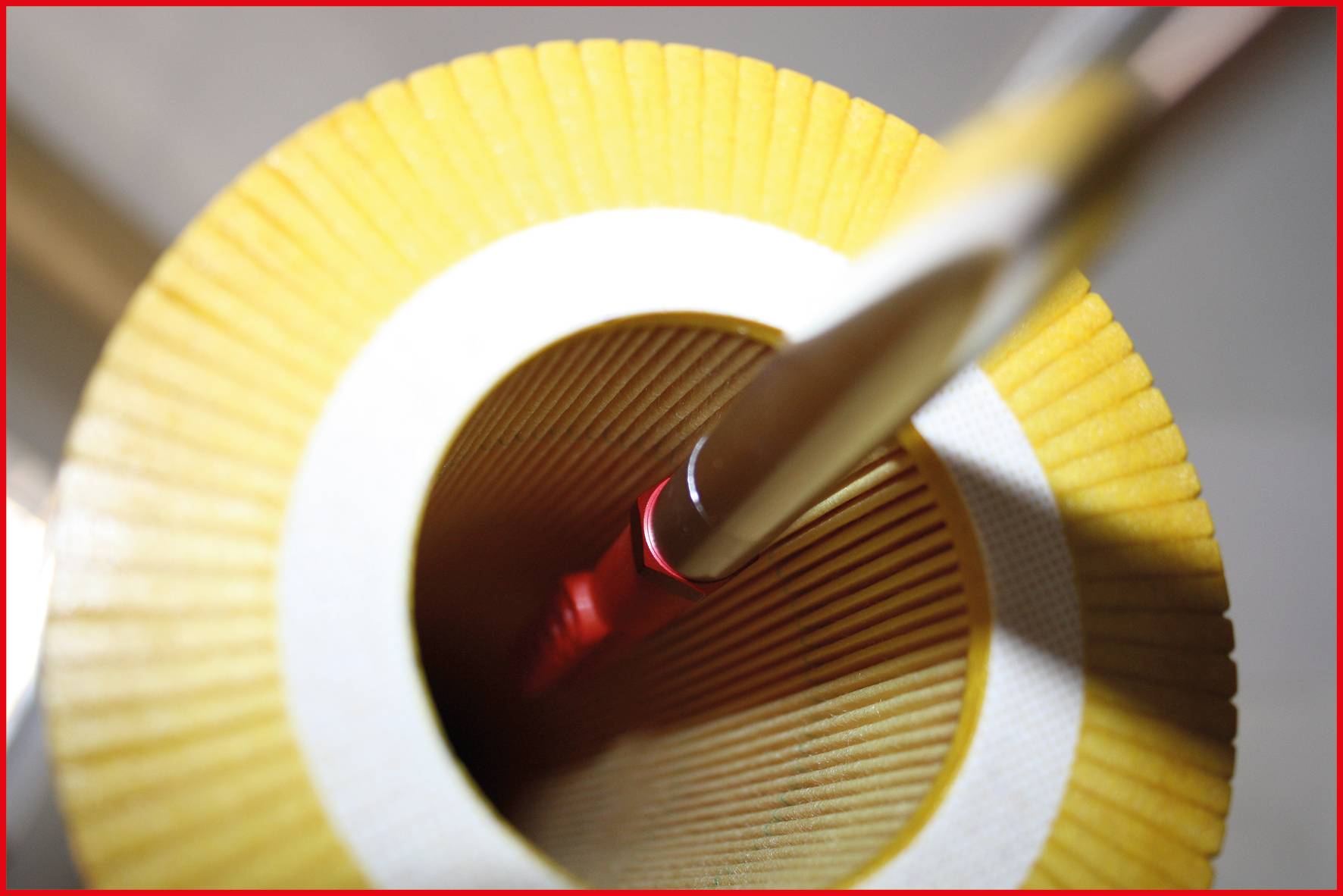 A view into a yellow, ridged paper roll with a red pencil inserted inside it.