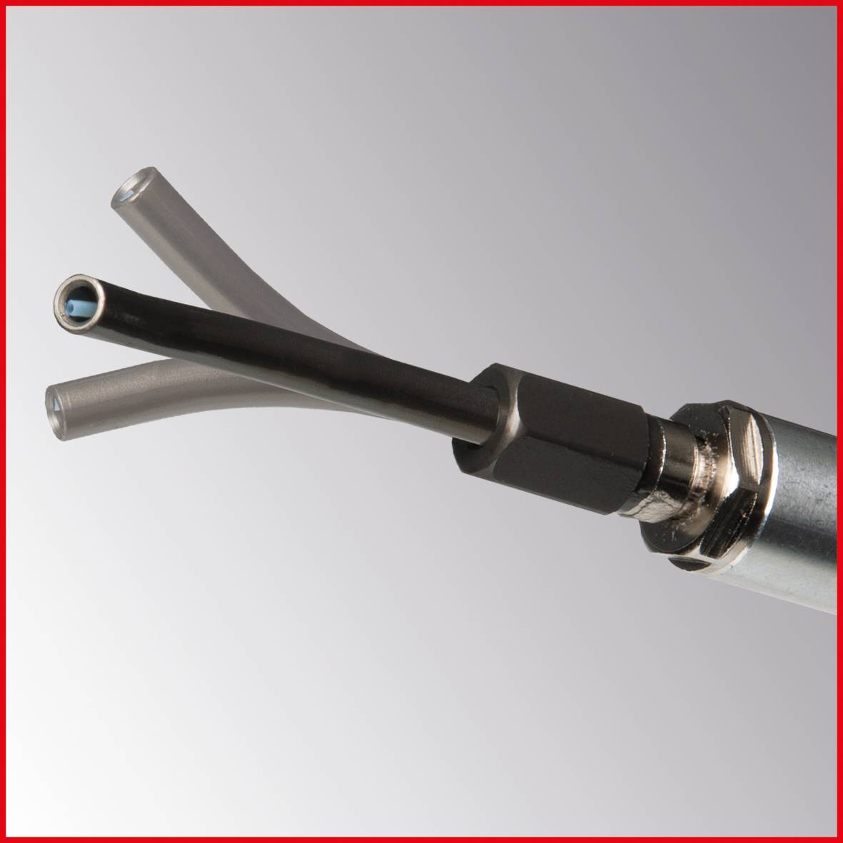 Three black cables with exposed ends protrude from a silver metal casing. The surrounding environment is a neutral grey-red.