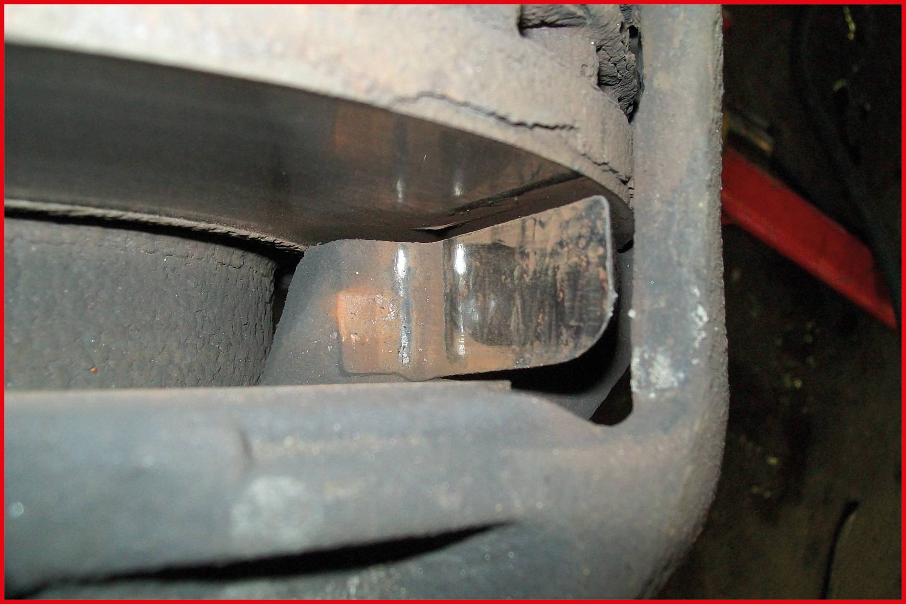 Close-up of a vehicle brake showing wear on the brake pads. A metal layer is clearly visible.