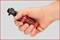 A hand is holding a red tool with a black handle. The tool appears compact and could be an impact driver.