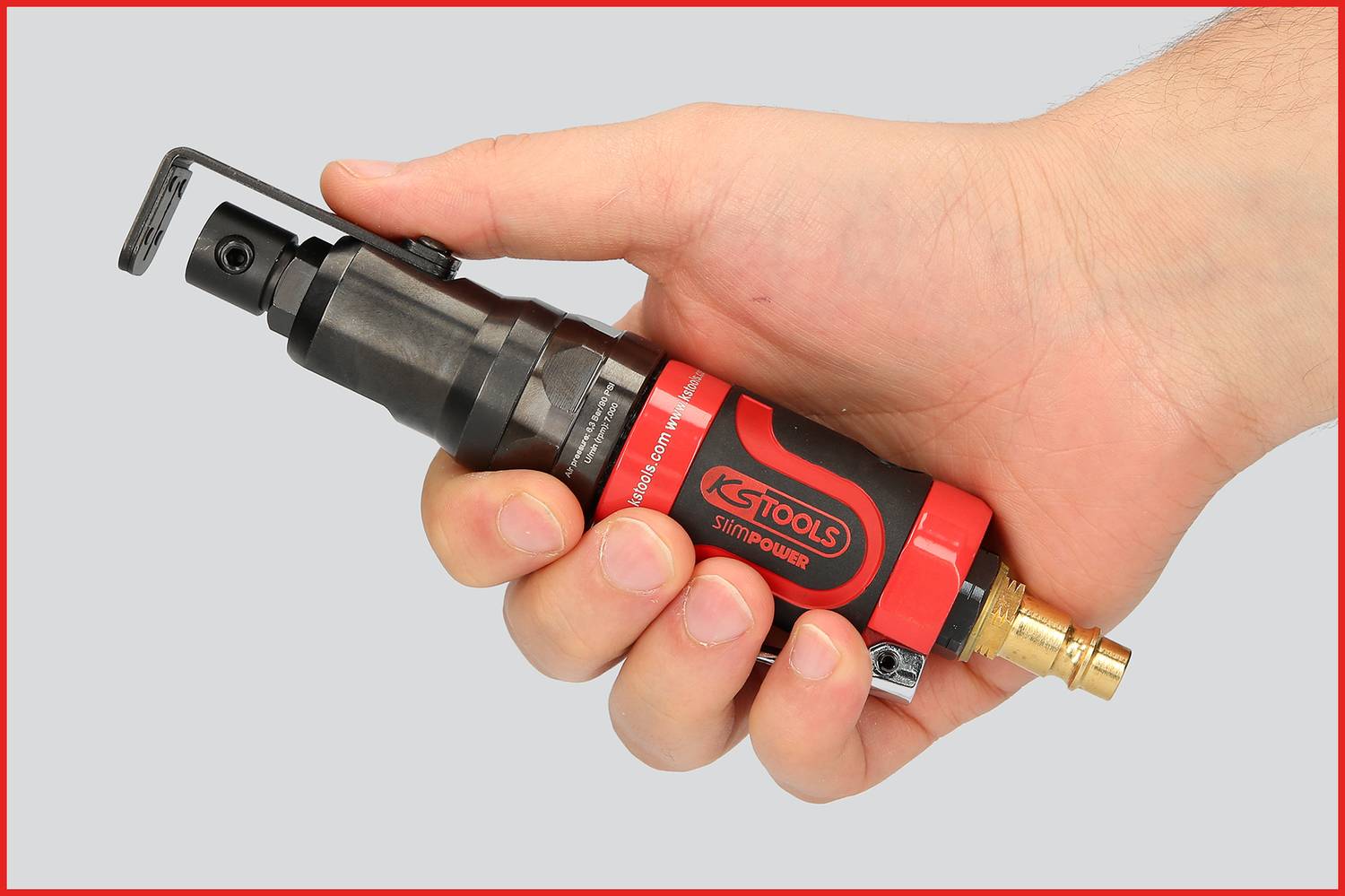A hand is holding a red KS Tools pneumatic tool with a black handle and brass connection, ready for use.