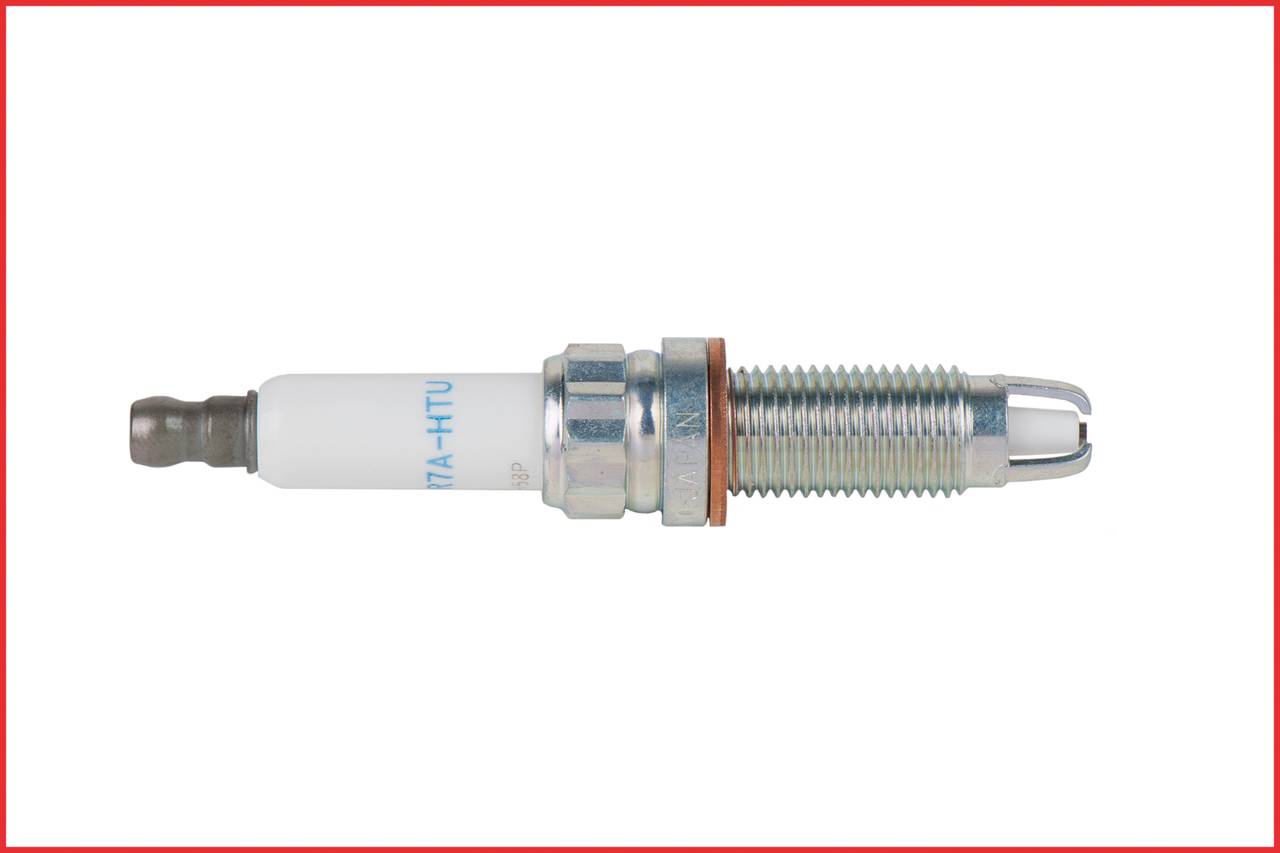 Metallic and ceramic spark plug on a white background, positioned horizontally. It has a thread and an insulator, typical of vehicle engines.