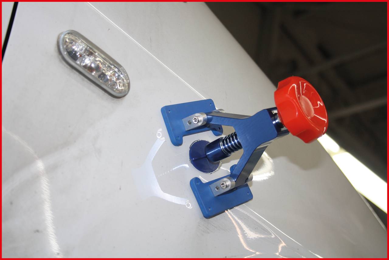 A blue and red suction cup tool is attached to a white surface. A LED light is visible in the top right corner.