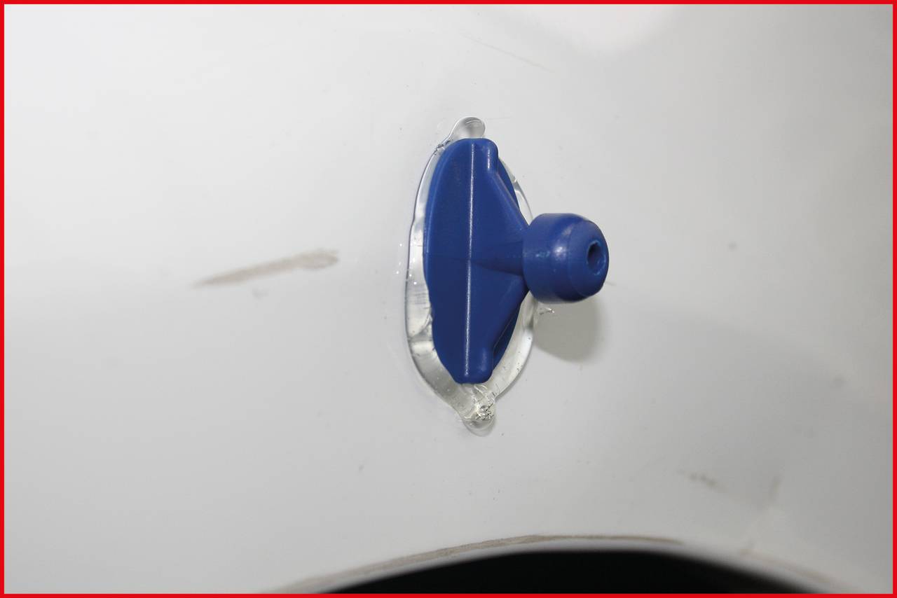 Blue plastic part attached to a white surface.