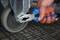 A hand is using pliers to adjust a screw on the wheel of a metal object.