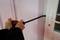 A person is attempting to force open a house door with a crowbar. The door is white and the background is out of focus.