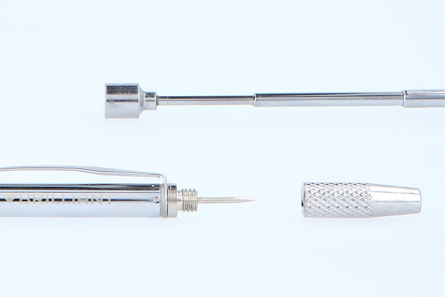 Disassembled metallic pen, comprising a tip, shaft, and removable cap, set against a light blue background.