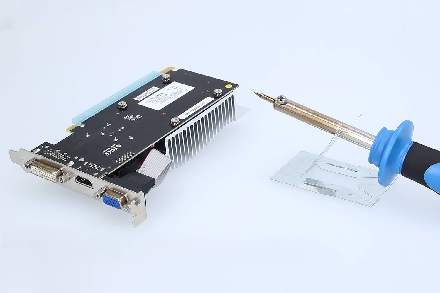 'Graphics card and soldering iron on a surface. The graphics card shows various ports, including DVI and VGA.'