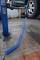 Car on a hydraulic lift with an air compressor for changing tyres. Blue spiral air hose on the floor.