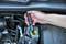 A hand is holding a test device over the brake fluid reservoir in a car to check the brake fluid.