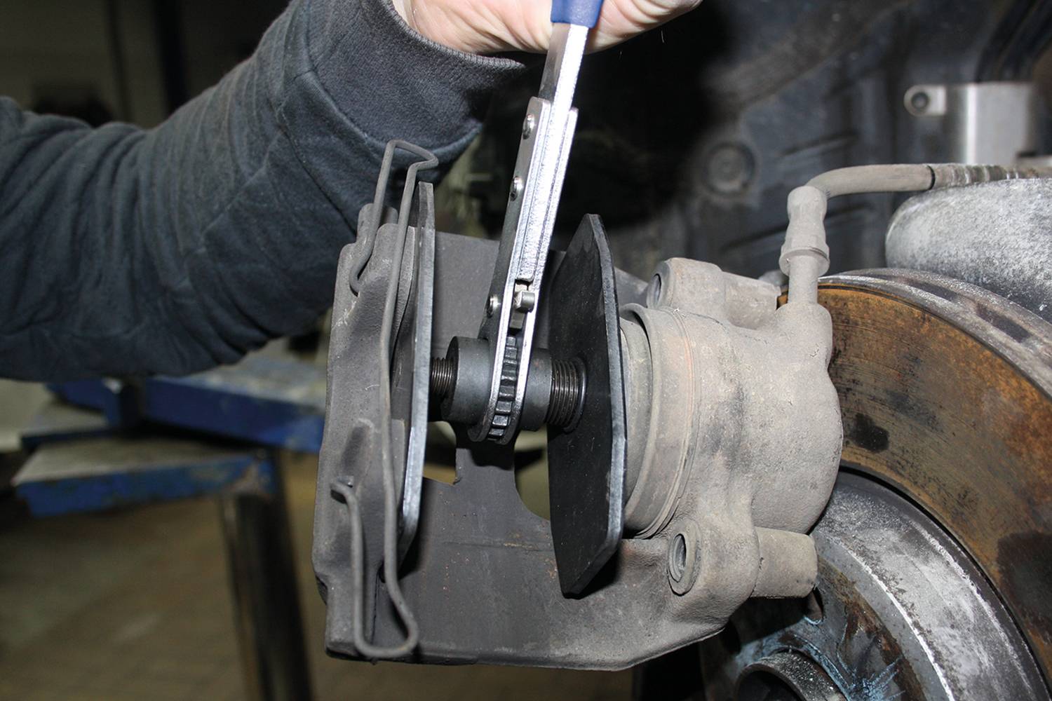 'Close-up of a person working with pliers on a brake disc to repair or service the brakes.'
