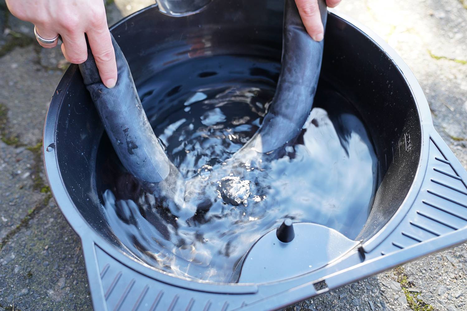 A person is washing a bicycle inner tube in a bucket of water to identify air bubbles and check for punctures.