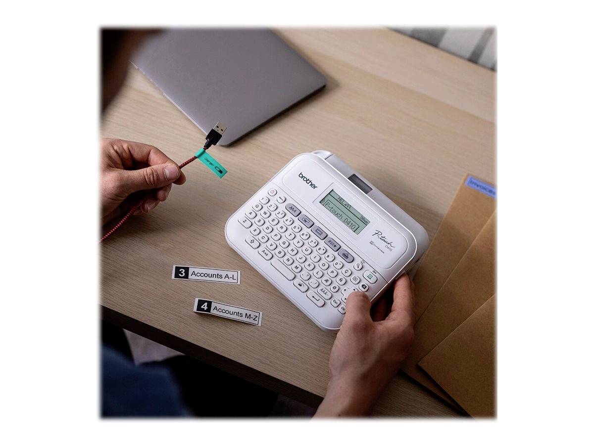A person is working with a label printer and labelling USB cables. A laptop and envelopes are lying on the table.