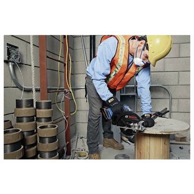 A construction worker in safety gear cuts metal on a wooden spool with a Bosch power tool in an industrial setting.