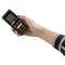 A hand is holding a portable measuring device with a display and several buttons. It shows measurement values for various parameters.