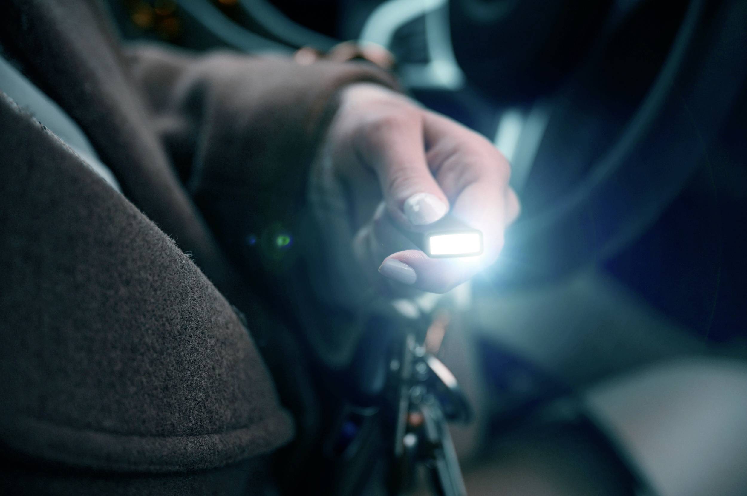 A person is holding an illuminated car key while sitting in the car.