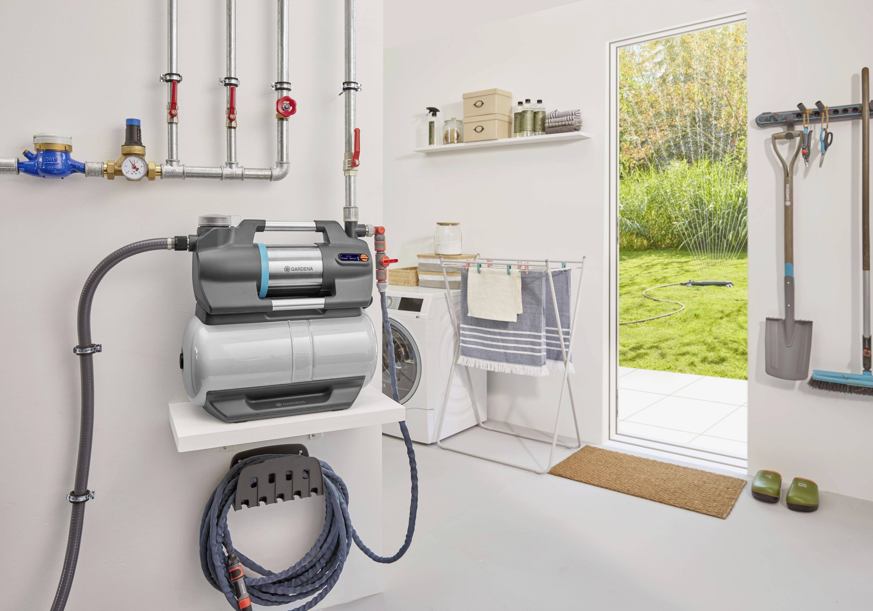 Utility room with a compact water filtration system mounted on the wall next to a washing machine. Window overlooking a green garden.