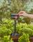 A hand adjusts a garden irrigation timer among lush green plants in a garden, illustrating automated watering control.