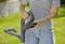 A person is holding a lawnmower handle in a garden. The focus is on the handling of the equipment.