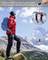 A person with a blue rucksack gazes into the distance in a mountainous landscape. Inserted images show skiing and paragliding.