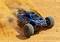 A remote-controlled car races across sandy terrain, kicking up dust and demonstrating its speed and manoeuvrability.