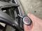 A hand is holding a tyre pressure gauge against a car tyre valve to check the air pressure.