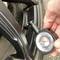 A pressure gauge is showing 2.5 bar of tyre pressure, and is being held by a hand and attached to a car tyre valve.