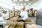 A person in protective clothing is inspecting food packaging in a factory. Production equipment can be seen in the background.