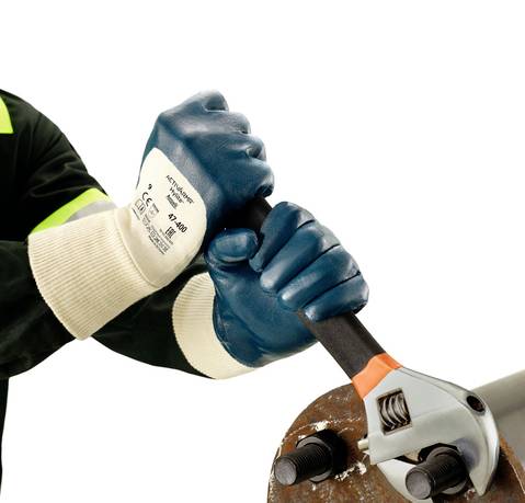 A person is tightening a pipe connection using a large pipe wrench while wearing blue gloves.