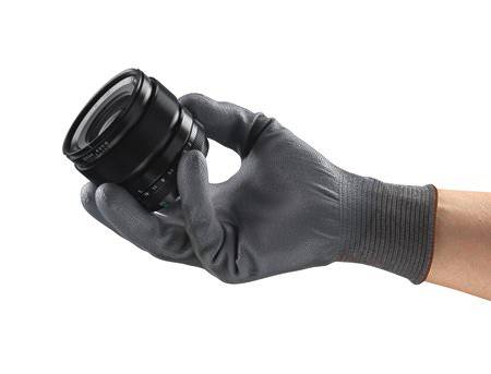 A hand wearing a grey glove is holding a camera lens.