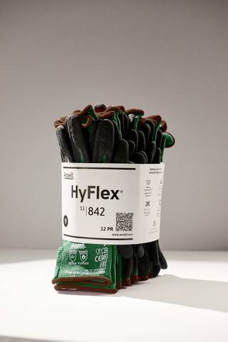 Stack of Ansell HyFlex work gloves, Model 11-842, on a table, with product packaging and QR code visible.