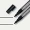 Two chalk markers, one with its cap removed, lie beside two drawn lines on a light background.