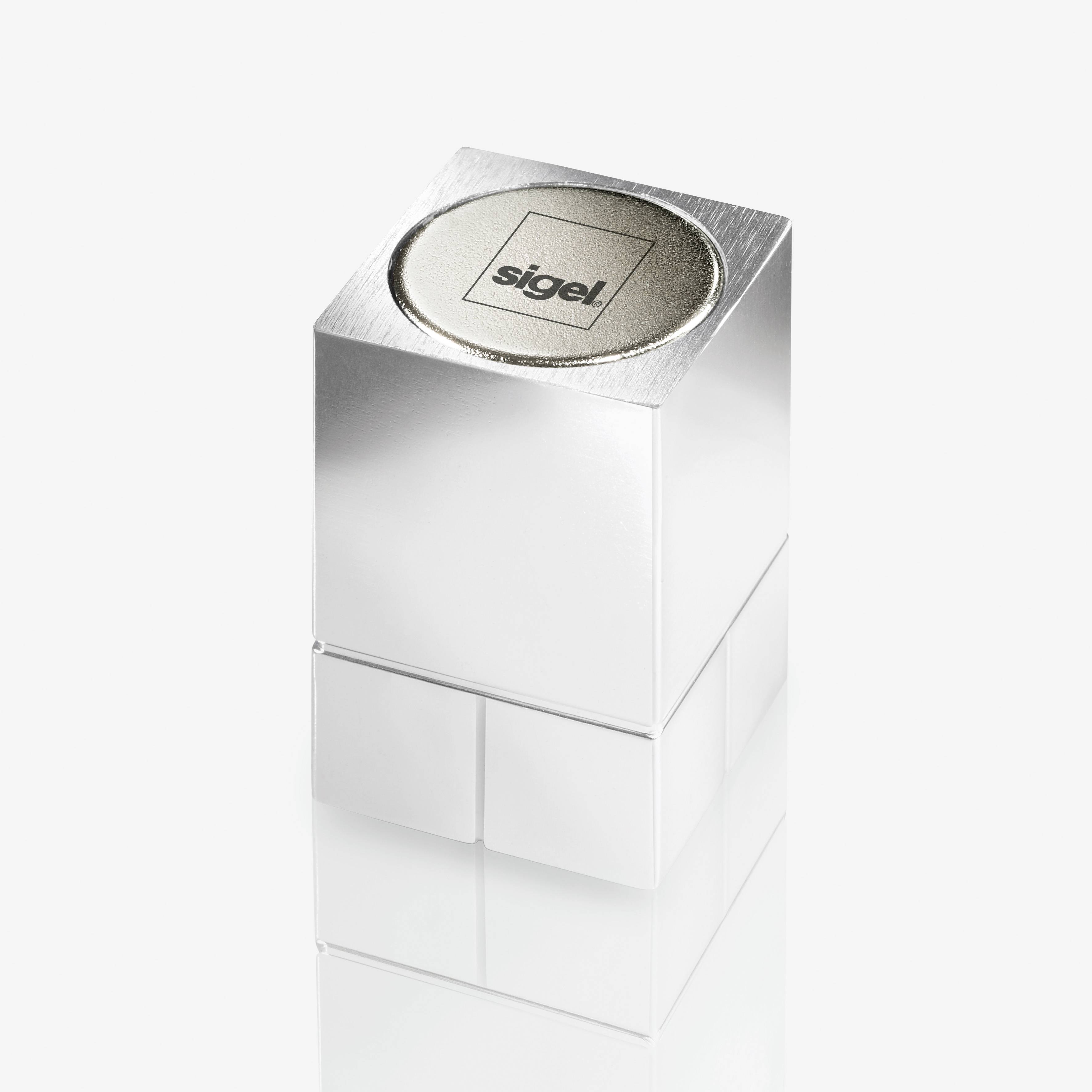 A silver metal stamp cube with a round surface for the stamp, bearing the inscription 'sigel'.
