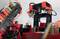 A robotic arm made of red and black components with cable connections is working in an industrial environment.