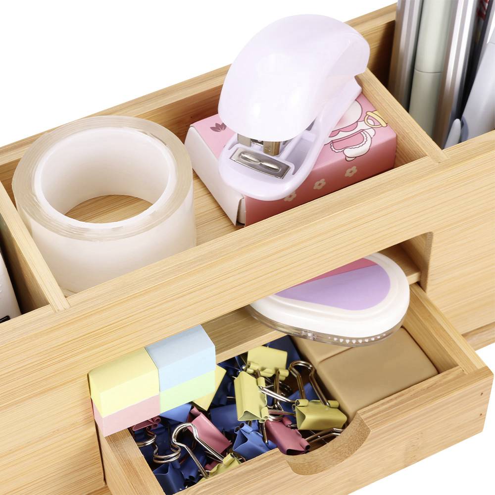 A wooden desk organiser with compartments designed to hold office supplies such as sellotape, paperclips, sticky notes, stapler and pens.