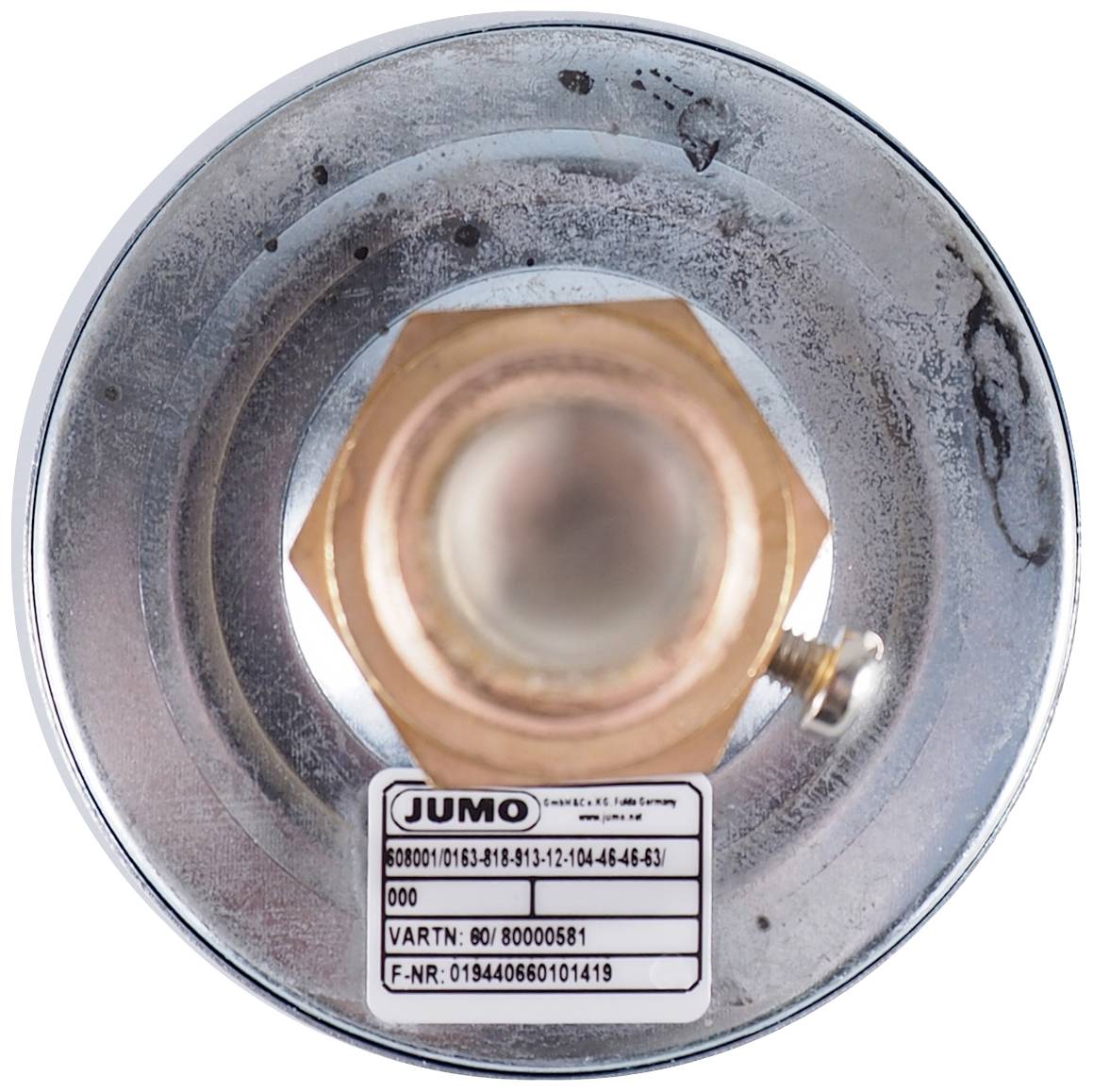 A round, silver metal cap with a central, golden hexagonal head. A label with technical data from the brand 'JUMO'.